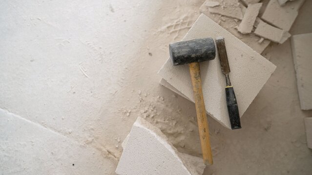 Hammer and chisel on broken stone blocks with dust scattered around