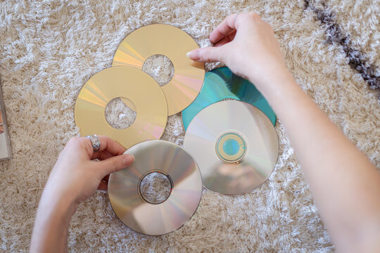 Woman arranging vintage cds and dvds on carpet