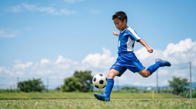 サッカーをする小学生の男の子 芝生のグラウンド コピースペース