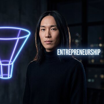 Confident young East Asian non-binary entrepreneur standing beside a glowing neon light bulb symbol
