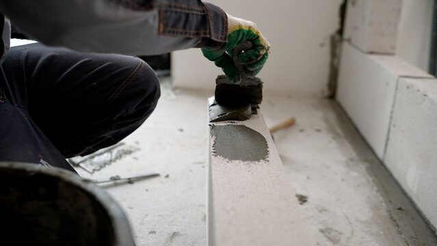 Construction worker applying mortar on aerated concrete block