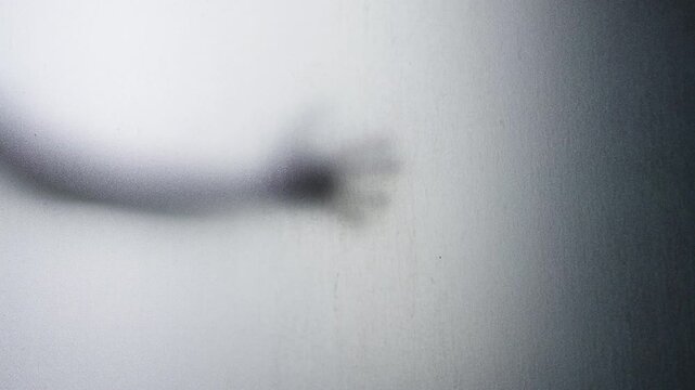 Blurred Human Hand Reaching Through Frosted Glass Against a Grainy Translucent Surface. Mysterious Presence, Fear, Suspense and Psychological Tension