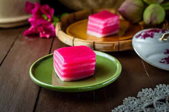 Traditional Southeast Asian pink layered sweet cake, known as Khanom Chan in Thai or Kueh Lapis in Malay culture, served on a green plate, representing authentic Peranakan culinary heritage.