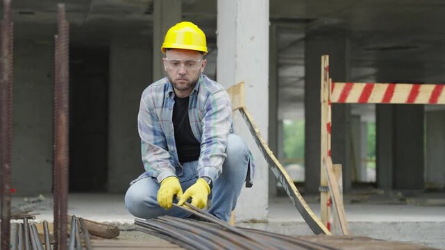 Construction worker tying steel rebar together at building site