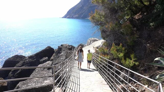 Italy , Liguria , Genoa La Spezia - mother and son walking by the sea -  the seaside path way  via del mare, seafront walk  in Framura close to Cinque Terre - tourist attraction destination for summer