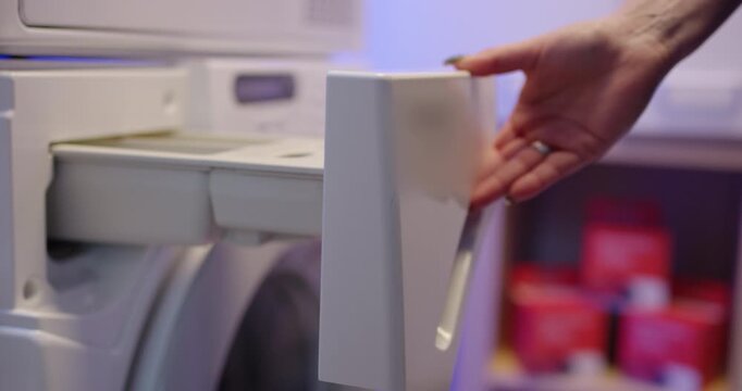 Interior view of a washing machine drum with white clothing and a red wool ball spinning during wash