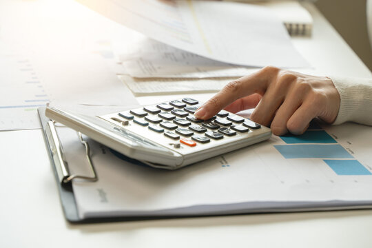 Women business people use calculators to calculate the company budget and income reports on the desk in the office.