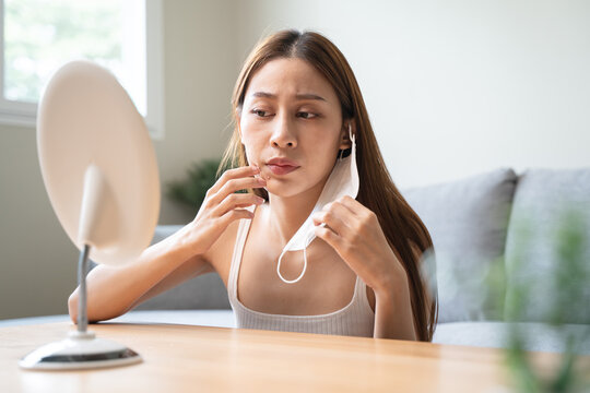 Asian young woman worry about acne on her face after wear face mask.