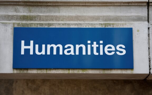 A blue sign on a stone wall with the word humanities in white letters