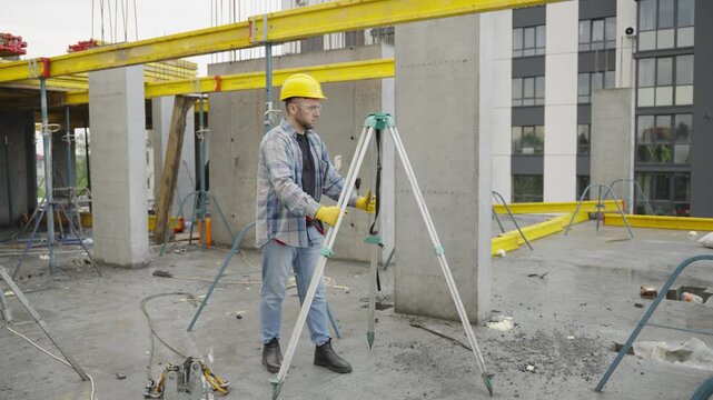 Surveyor using optical level theodolite at construction site