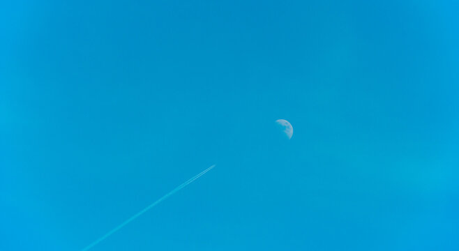 Airplane flying along the moon in a blue sky, Almere, Flevoland, The Netherlands, June 22, 2026