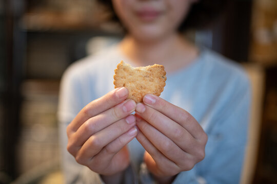 かじったビスケットを両手で持つ女の子の手元 - おやつ・幸せな日常