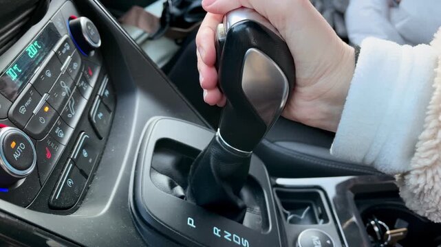 Close up of female driver moving automatic transmission selector into drive mode before starting journey. Vehicle operation, driving preparation, transportation and mobility concept.