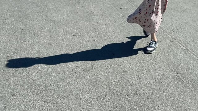 A Caucasian woman with mild cerebral palsy walks down the street. Close-up of legs.