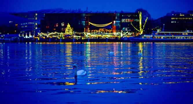 Die hell erleuchtete Uferpromenade mit Schw&auml;nen auf dem Vierwaldst&auml;ttersee bei Nacht in Luzern, Schweiz