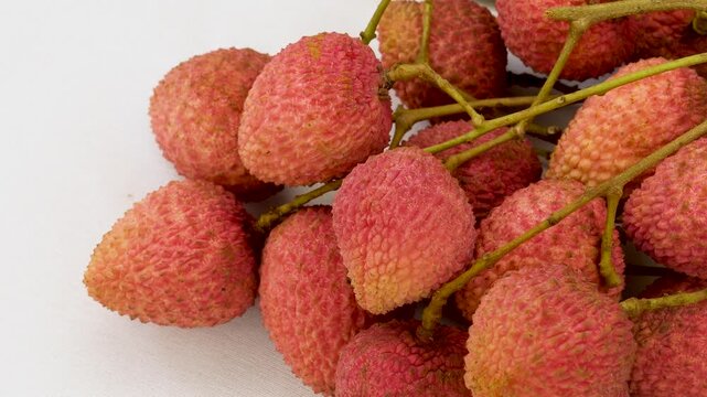 A cluster of fresh ripe red Litchi or lychees fruits with green leaves branch, its fruits is sweet and juice, isolated on a white background.