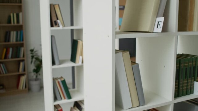 Bookshelves holding organized books being filmed with slow camera pan. Video serves as educational B-roll for student integration programs or library marketing