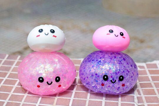 Four kawaii squishy dumpling toys stacked in pairs on tiled surface including glitter and plain versions