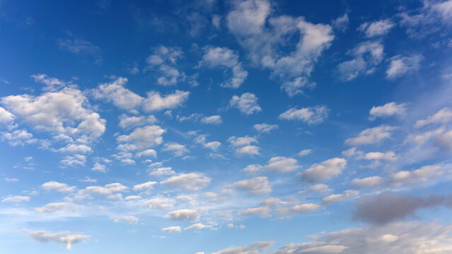 White scattered cumulus clouds in deep blue clear sky