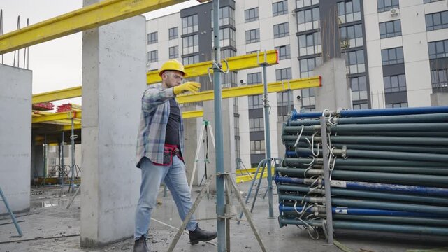 Construction worker adjusting scaffolding prop on building site