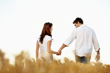 Obraz premium Couple, holding hands and back with walking outdoor, partner and support with care in nature. People, marriage and romantic stroll in meadow for healthy relationship, bonding and together with space