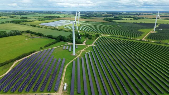 Aerial view of Chelveston Renewable Energy Park combining co-located solar panel arrays and wind turbines in Northamptonshire, UK.