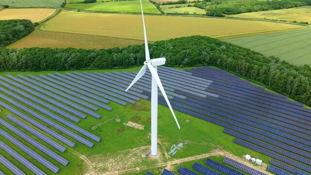 Aerial view of Chelveston Renewable Energy Park combining co-located solar panel arrays and wind turbines in Northamptonshire, UK.