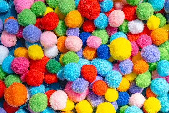 Colorful pompom balls arranged as a vibrant abstract background with soft texture and bright multicolored pattern.
