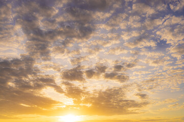 Fototapeta premium Golden sunset sky with soft scattered clouds,A breathtaking view of the golden sunset sky featuring soft, scattered clouds illuminated by the warm light of the setting sun, creating a peaceful.