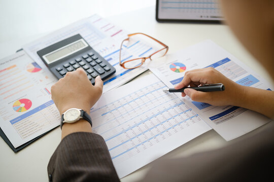 Businesswoman analyzing financial reports with calculator and pen, concept of accounting, budgeting, and business planning.