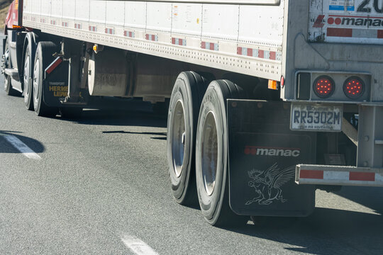 Quebec, Canada, 24 April 2026 : A semi-trailer truck with a white trailer and Manac mud flaps travels on a highway.