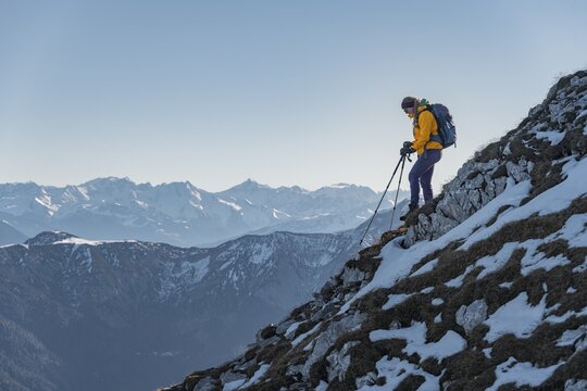 Climber on a ledge, snow-covered mountains, hiking to the Guffert in winter, Brandenberg Alps, Tyrol, Austria