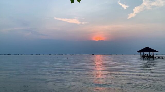 Ultra HD 4K sunrise timelapse over calm sea at Tanjung Lesung Beach, Banten, Indonesia. Peaceful morning scene with gazebo and reflections, suitable for travel, nature, wellness, and vacation themes.