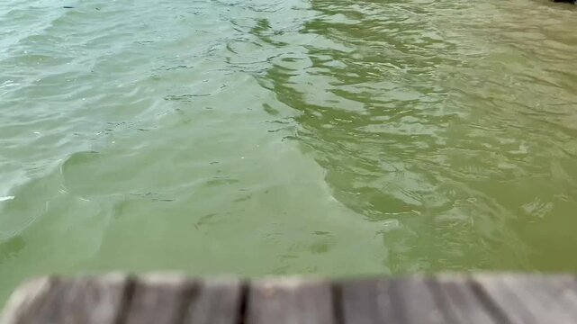 4K close-up of gentle morning water ripples at Tanjung Lesung Beach, Banten, Indonesia. Calm coastal texture viewed from a wooden pier, ideal for nature, wellness, travel and background themes.