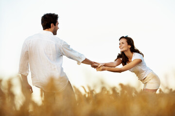 Obraz premium Couple, holding hands and happy outdoor in meadow on date, partner and support with fun in nature. People, marriage and playful for healthy relationship, bonding and together with smile for love