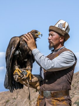 Traditional Kyrgyz eagle hunter with eagle in the mountains, hunting, near Bokonbayevo, Issyk Kul region, Kyrgyzstan
