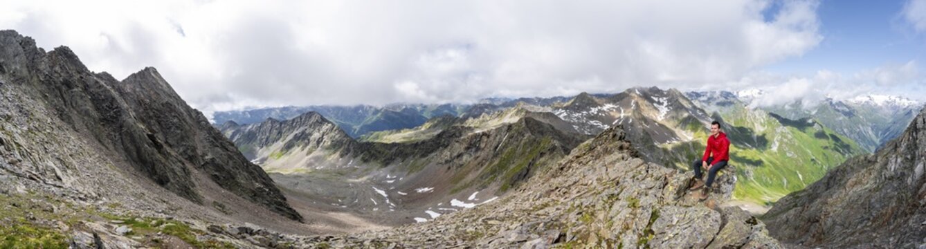 Panorama, mountaineer sitting on a rock, on a steep rocky ridge, on the summit of the Las&ouml;rling, view of the mountain panorama of the Venediger group, Las&ouml;rling group, Hohe Tauern National Park, East Tyrol, Tyrol, Austria