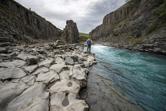 Tourist standing by the river in Stu&eth;lagil Canyon, turquoise blue river between basalt columns, Egilsstadir, Iceland