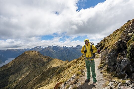 Hiker on Kepler Track, Great Walk, view of the South Fiord of Lake Te Anau, Murchison Mountains in the background, Fiordland National Park, Southland, New Zealand