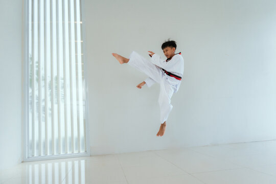 Young person practices martial arts moves in a bright training space during the day
