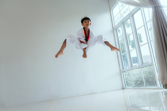 Young person practices martial arts moves in a bright training space during the day