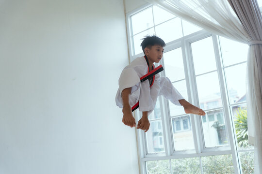 Young person practices martial arts moves in a bright training space during the day