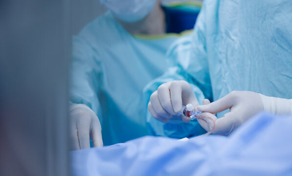Closeup of surgeon hands inserting catheter during cardiac procedure for clinical medical