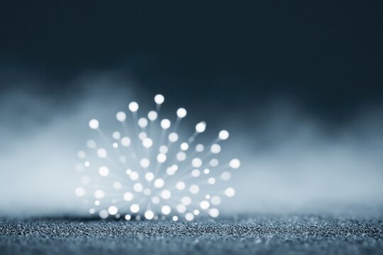 Light spots form a pattern on a gray surface with a dark background in a foggy setting during nighttime