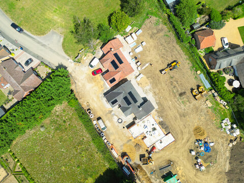 Interesting drone UAV view of a new detached bungalows being built within a small building plot in Cambridgeshire, UK. Established homes surround the site.