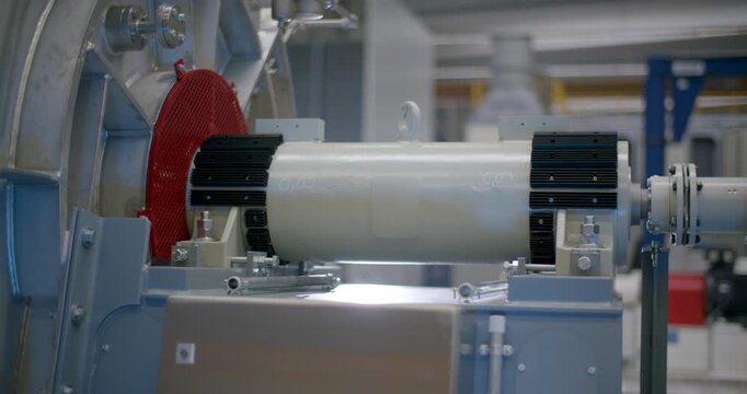 Close up of a horizontal industrial drive shaft connected to a large motor and machine