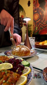 Waiter cutting a traditional Moroccan pastilla dish with a knife in a restaurant
