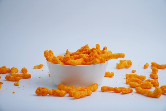 puffcorn cheese snacks in a white plastic bowl with an isolated white background