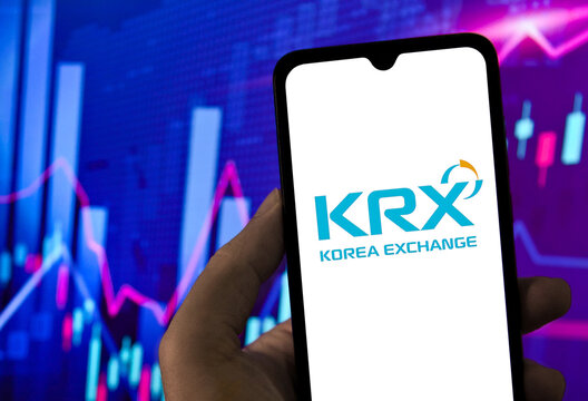 Smartphone displaying Korea Exchange KRX logo on screen with financial stock market chart background