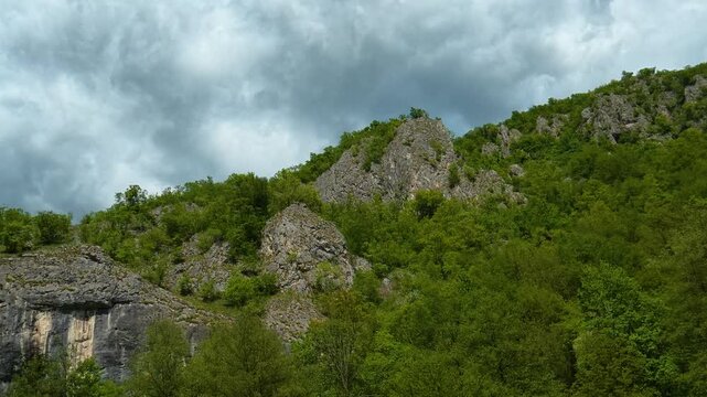 Rugged cliffs rise amid dense green foliage. Gradac River, Serbia